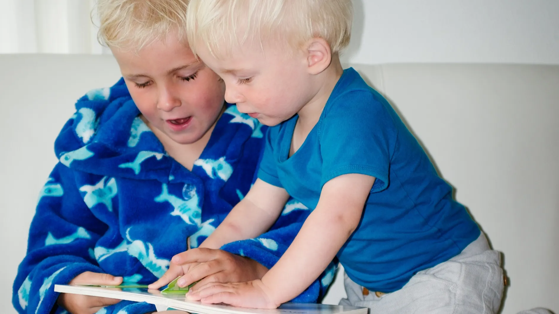 Boys in blue pajamas engrossed in reading, reminding us to embrace language learning mistakes without fear.