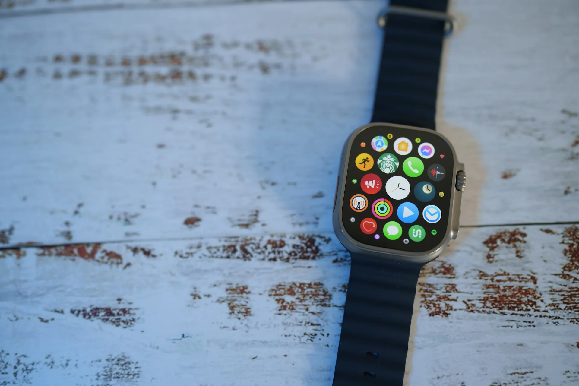 A modern Apple Watch, complete with a touch screen and various apps, is placed on a natural wooden table.