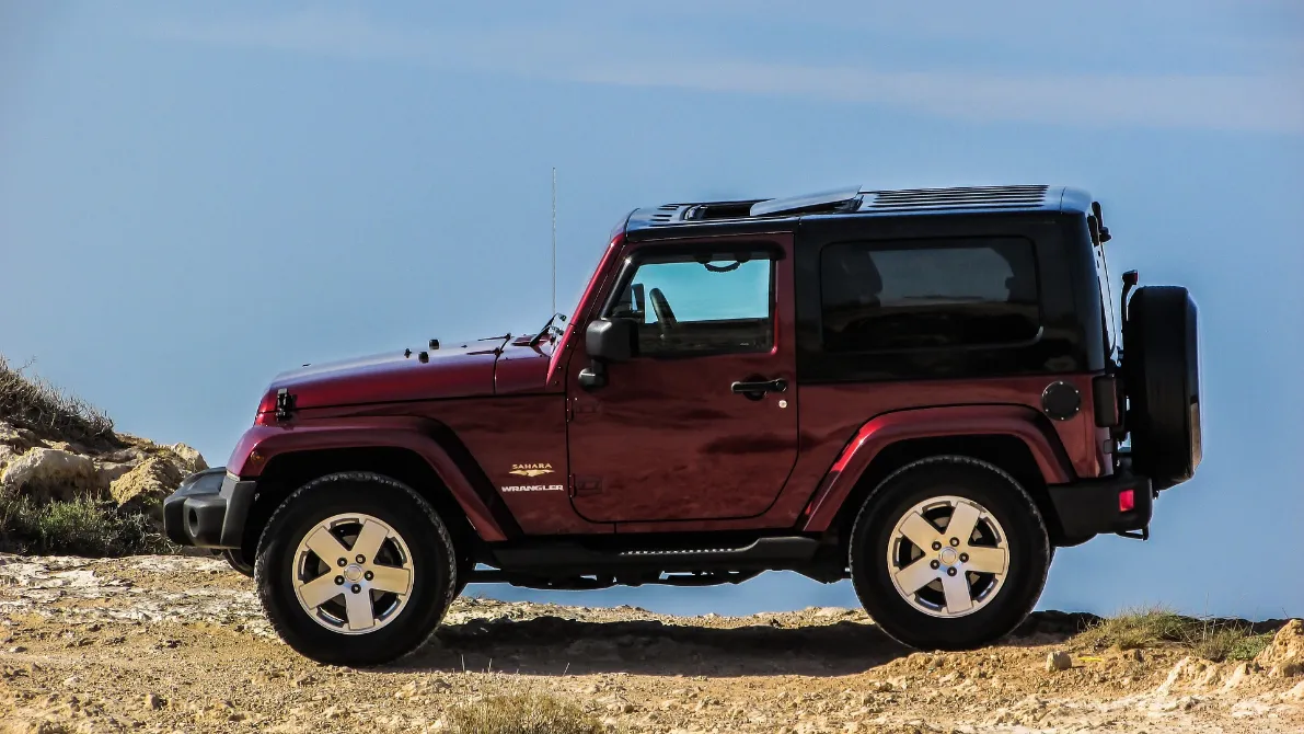Red jeep parked on rocky hill, showcasing the versatile SUV for all your needs.