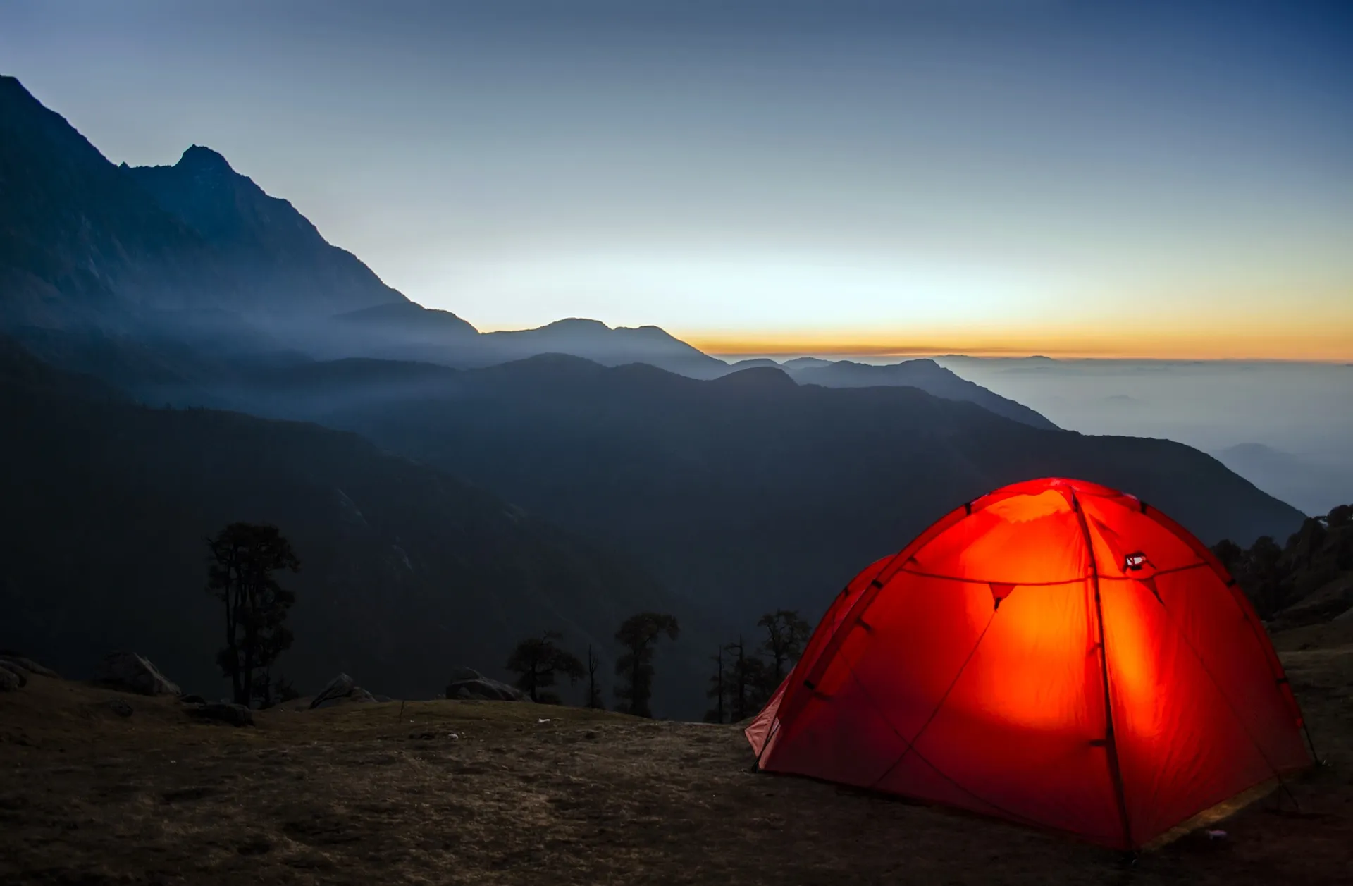 A tent is set up on top of a mountain, prepared for all types of weather