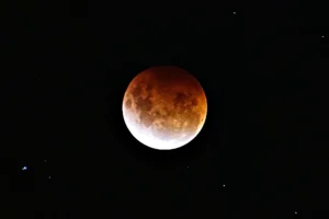 A red blood moon during a total lunar eclipse, with the text "Witness the Beauty of a Lunar Eclipse Safely."
